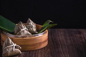 zongzi - kinesisk ris klimp zongzi i en ångkokare på trä- tabell svart retro bakgrund för drake båt festival firande, stänga upp, kopia Plats. foto