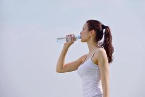 ung vacker kvinna dricksvatten efter fitness träning foto