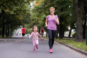 mor och liten dotter joggning i stad parkera foto