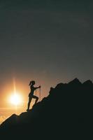 kvinna klättrar bland stenar i en färgrik berg solnedgång foto