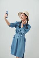 emotionell ung kvinna tar selfie på vit bakgrund foto