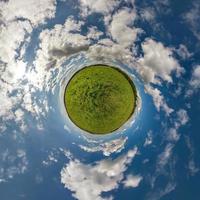 grön liten planet i blå himmel med vackra moln. transformation av sfäriskt panorama 360 grader. sfärisk abstrakt flygfoto. utrymmets krökning. foto