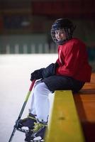 barn is hockey spelare på bänk foto