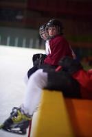 barn is hockey spelare på bänk foto