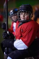 barn is hockey spelare på bänk foto