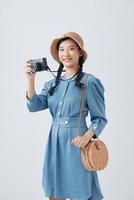 ung asiatisk kvinna innehav en årgång kamera på vit bakgrund foto