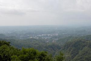 kulle Drönare skott av en stad landskap. bandarban stad är i de mitten av de berg. urban område fotografi i en kuperad landskap. skön naturlig scen med en molnig himmel och stor kullar. foto