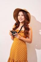 attraktiv ung kvinna med en Foto kamera i henne hand på ett isolerat beige bakgrund. de begrepp resa