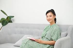 ung kvinna läsning humoristisk ny medan Sammanträde på soffa foto