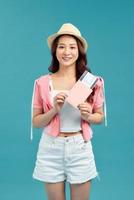 ung kvinna innehav pass, kreditera kort. leende flicka resande på blå bakgrund. foto