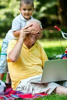 farfar och barn använder sig av bärbar dator foto