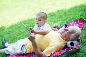 farfar och barn i parkera använder sig av läsplatta foto