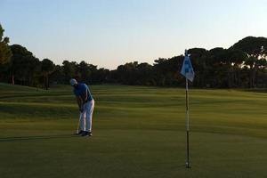 golfspelare slå boll till hål foto