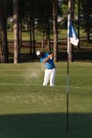 proffs golfspelare slå en sand bunkra skott foto