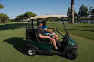 golf spelare körning vagn på kurs foto