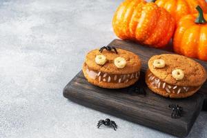 kakor med gräddpasta i form av monster för halloween-firande. roliga hemgjorda ansikten gjorda av havregrynskakor och kokt kondenserad mjölk. kopieringsutrymme foto