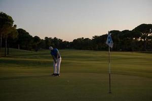 golfspelare slå boll till hål foto