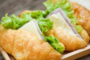 croissant smörgåsar på trä- tabell - stänga upp croissant sallad skinka vegetabiliska foto