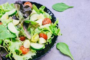hälsosam sallad grönsaksblad blanda sallad med frukt och färsk sallad tomat gurka på tallrik på bordet färsk mat äta foto