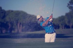 proffs golfspelare slå en sand bunkra skott foto