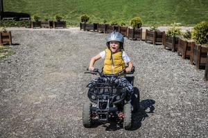 små pojke har roligt medan körning quad cykel på smuts väg. foto