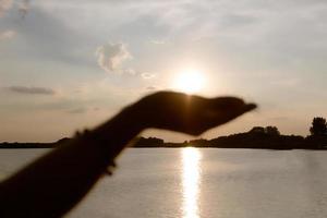 stänga upp av kvinna innehav Sol i henne hand på solnedgång. foto