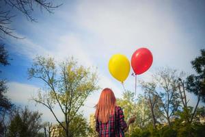 bak- se av kvinna med färgrik ballonger gående i de parkera. foto