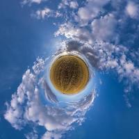 grön liten planet i blå himmel med sol och vackra moln. transformation av sfäriskt panorama 360 grader. sfärisk abstrakt flygfoto. utrymmets krökning. foto