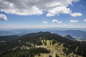 klarblå himmel och tjockt lager av vita fluffiga moln som svävar över gröna berg i bulgarien. foto