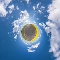 liten planet i blå himmel med sol och vackra moln. transformation av sfäriskt panorama 360 grader. sfärisk abstrakt flygfoto. utrymmets krökning. foto