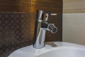 vit keramisk tvättställ med vatten kran handfat med kran i dyr badrum foto