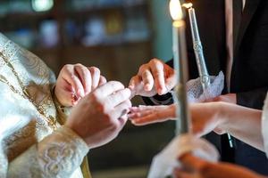 de präst hjälper de nygifta utbyta ringar på de bröllop ceremoni i de kyrka foto