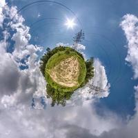 grön liten planet omvandling av sfärisk panorama 360 grader. sfärisk abstrakt antenn se i fält med hög Spänning elektrisk pylon torn och grymt bra skön moln. krökning av Plats. foto