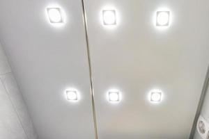 undertak med halogenspotslampor och gipskonstruktion i tomt rum i lägenhet eller hus. sträcktak vit och komplex form. foto