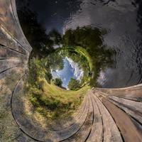 abstrakt inversion av liten planet omvandling av sfärisk panorama 360 grader. sfärisk abstrakt antenn se på trä- bro nära flod. krökning av Plats. foto