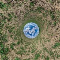 blå himmel boll i mitten av virvlande grön fält. inversion av mycket liten planet omvandling av sfärisk panorama 360 grader. krökning av Plats. foto