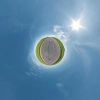 grön liten planet i blå himmel med vackra moln. transformation av sfäriskt panorama 360 grader. sfärisk abstrakt flygfoto. utrymmets krökning. foto