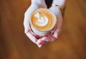 stänga upp händer av Barista kvinna innehav kopp av varm cappuccino kaffe i de Kafé foto