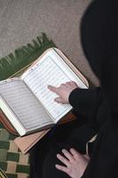 mitten östra kvinna bön- och läsning de helig quran foto