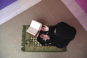 mitten östra kvinna bön- och läsning de helig quran foto