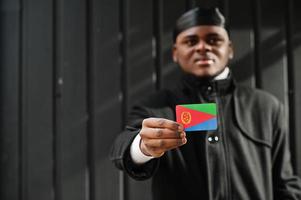 afrikansk man ha på sig svart durag håll eritrea flagga på hand isolerat mörk bakgrund. foto