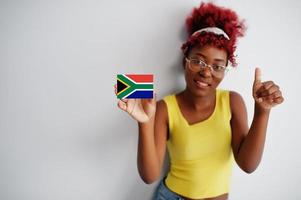 afrikansk kvinna med afro hår, ha på sig gul undertröja och glasögon, håll söder afrika flagga isolerat på vit bakgrund, visa tumme upp. foto