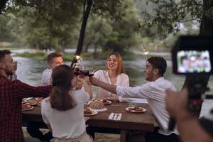 vänner toasting röd vin glas medan har picknick franska middag fest utomhuskameraman uppgifter en grupp av vänner har lunch foto