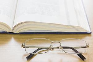 närbild glasögon och en bok på skrivbordet foto