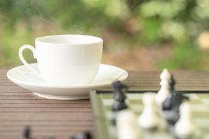 kaffe kopp på tabell med schack styrelse foto