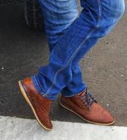 man bär blå denim jeans med brun läder skor. foto