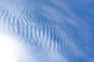 vita moln som en havsvågform på den ljusblå himlen som bakgrund. foto