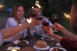 vänner toasting röd vin glas medan har picknick franska middag fest utomhus- foto