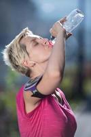 kvinna dricka vatten efter joggning foto