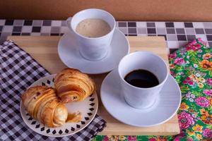 kopp av kaffe och croissant foto